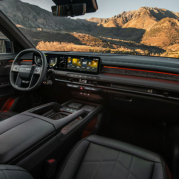 Side view of the 2027 Kia Telluride X-Pro in matte brown parked in a grassy field with snow-capped mountains in the background.