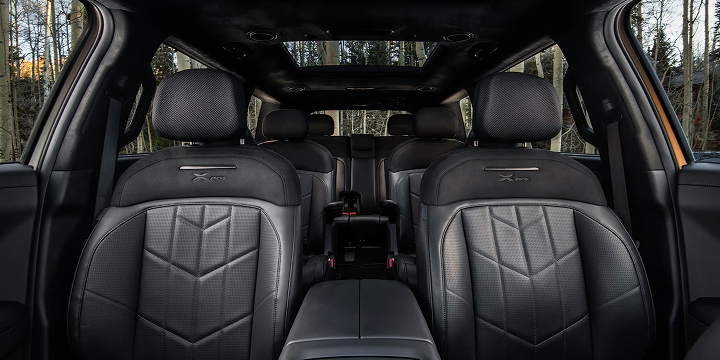 Interior view of the 2027 Kia Telluride X-Pro in black showcasing the 8-passenger seating layout with premium leather chairs. Forest views are peaking out of the windows and sunroof highlighting the SUV’s spacious design.