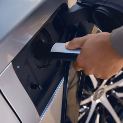 A person plugs a charger into their vehicle’s charging port.
