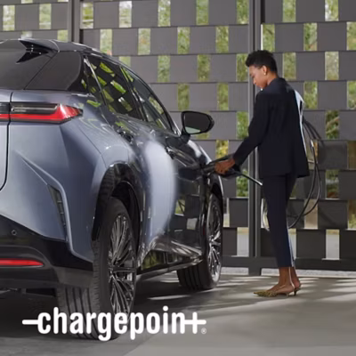 A person plugs a charger into their vehicle’s charging port.
