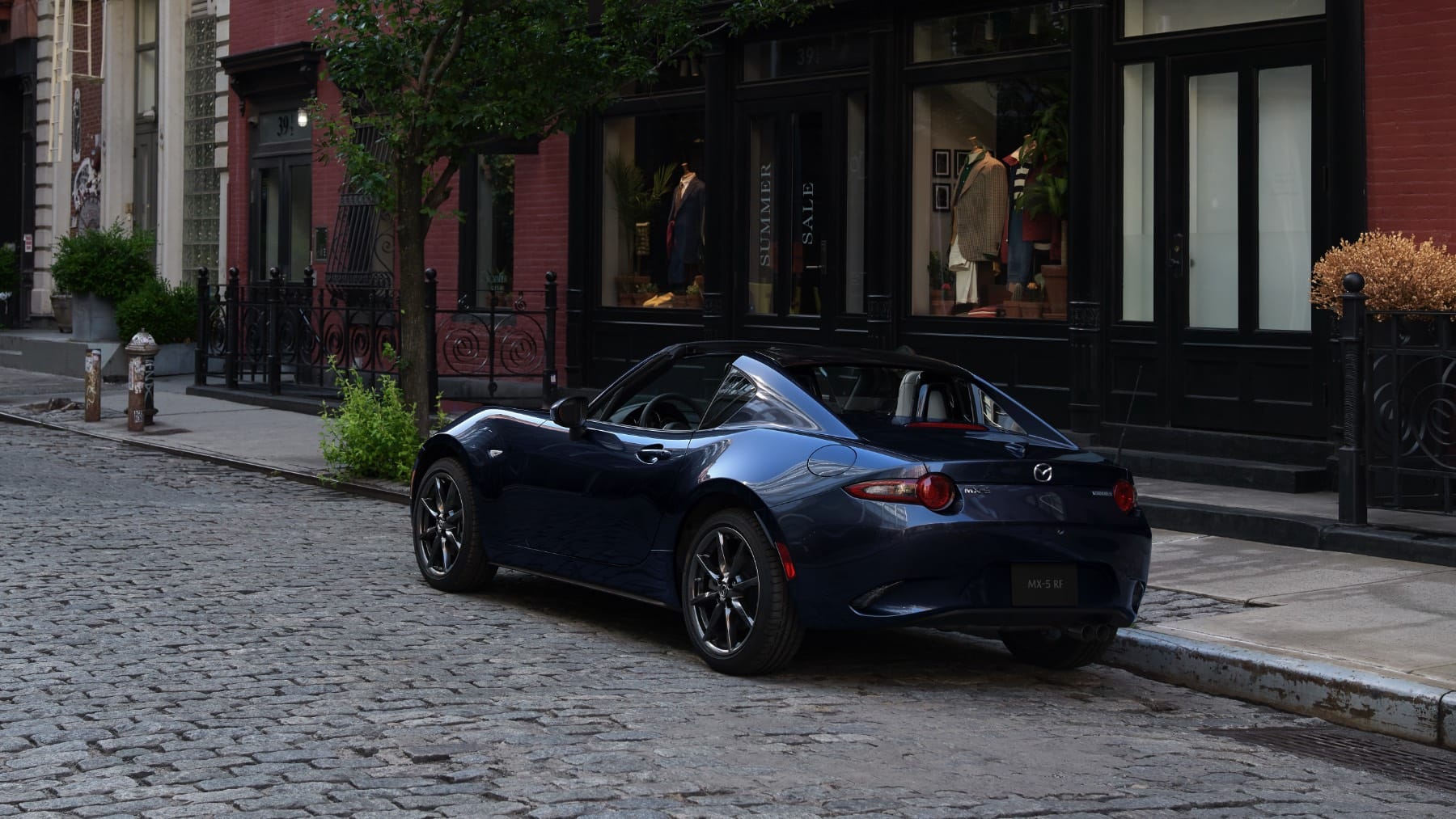 Miata parked in front of restaurant on cobble stone street