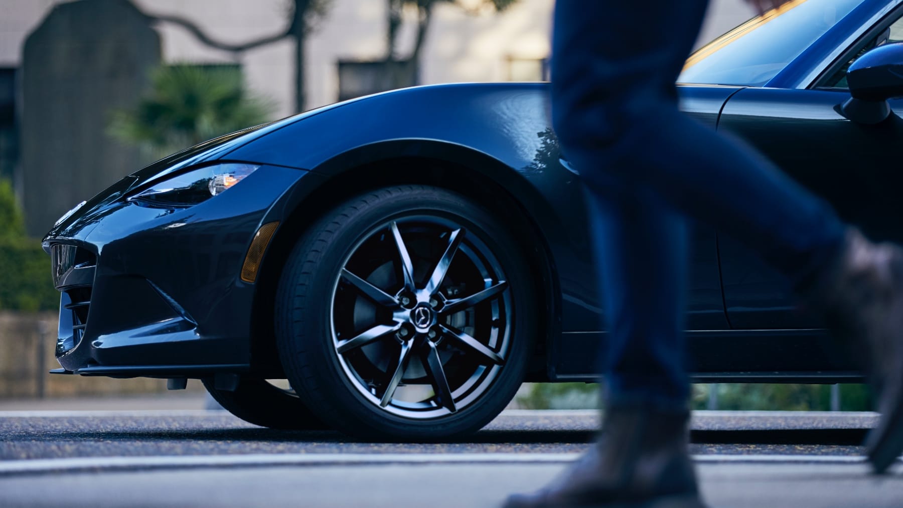 Front of parked Miata with woman walking in front of it