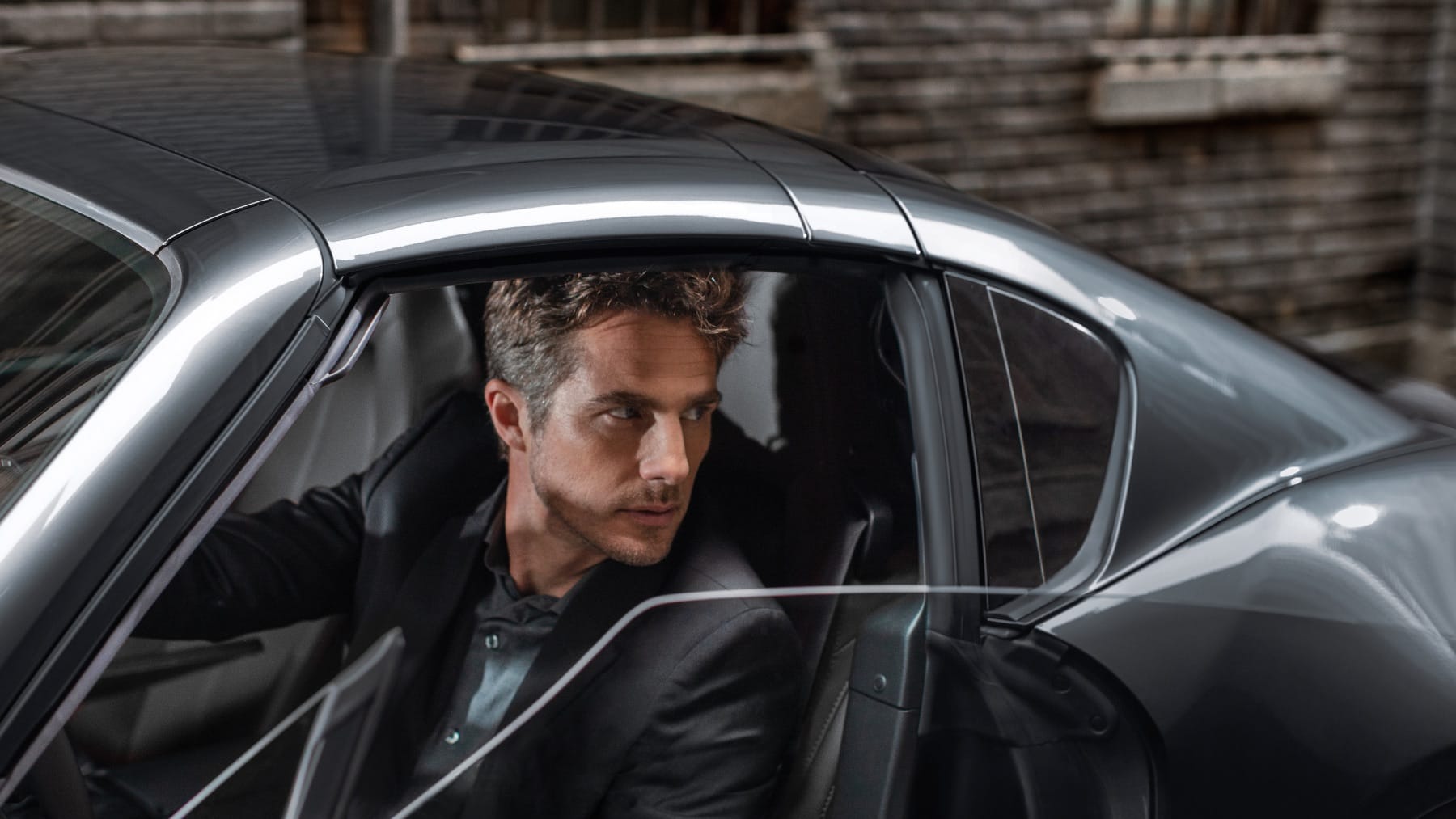 Man in parked car with door open looking backwards
