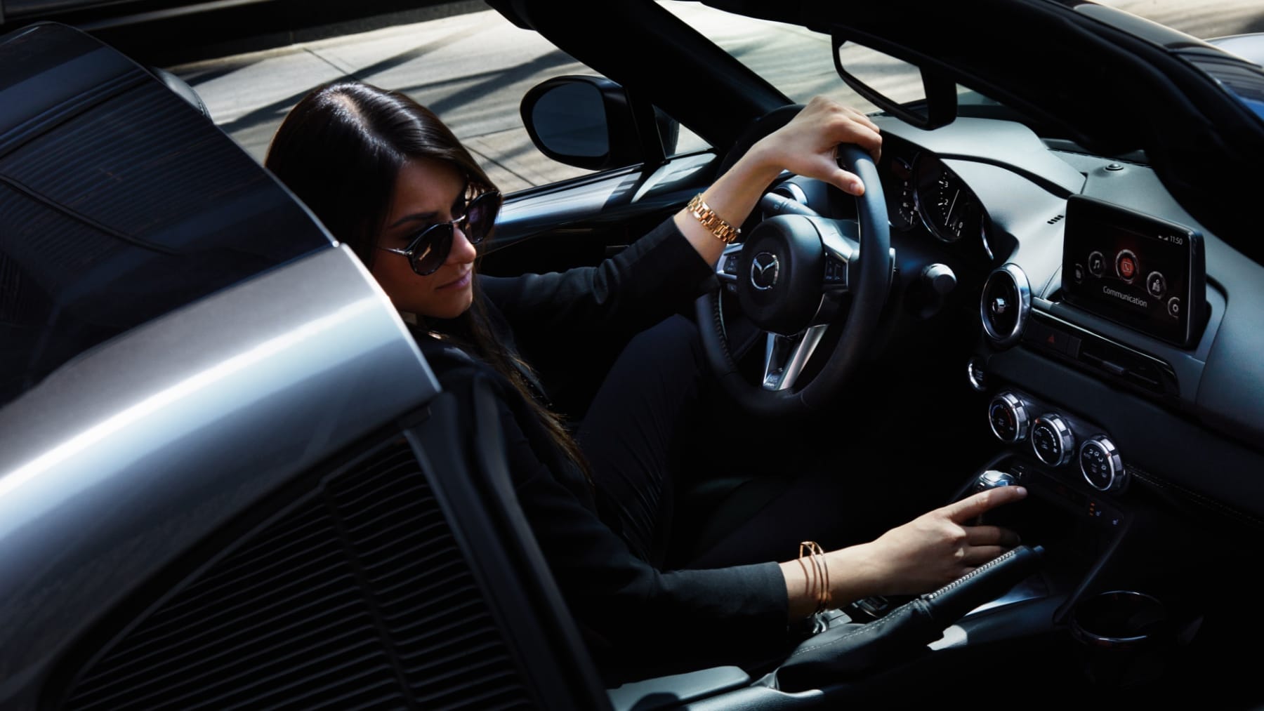 Woman with convertible top down driving car looking towards sidewalk